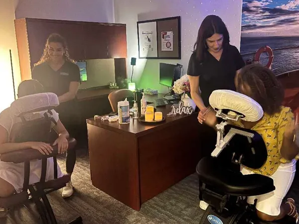 Two licensed massage therapists providing chair massage in a workplace